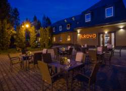 Letni ogródek restauracji w wieczornym oświetleniu, na ścianie budynku neon Bukova