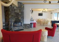 Sala kominkowa - czerwone fotele, drewniane krzesła i stoły, kominek obłożony kamieniem