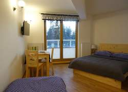 Sypialnia - łóżko małżeńskie z szafirową kapą oraz lóżko pojedyncze, drzwi balkonowe, stolik i krzesła z jasnego drewna