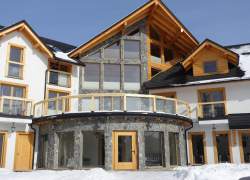 Widok zewnętrzny obiektu, znaczne przeszklenie, biały tynk i szary kamień