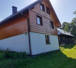Widok zewnętrzny domu - biała podmurówka, budynek drewniany