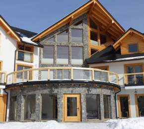 Widok zewnętrzny obiektu, znaczne przeszklenie, biały tynk i szary kamień