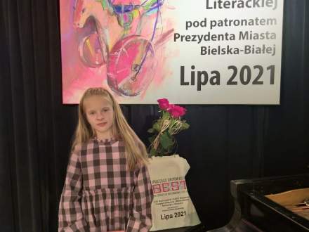 Hanna Nosowicz na tle plakatu z Przeglądu Dziecięcej i Młodzieżowej Twórczości Literackiej