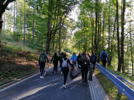 Młodzież z klasy 2a LO w Wiśle idąca asfaltową drogą pośród lasu