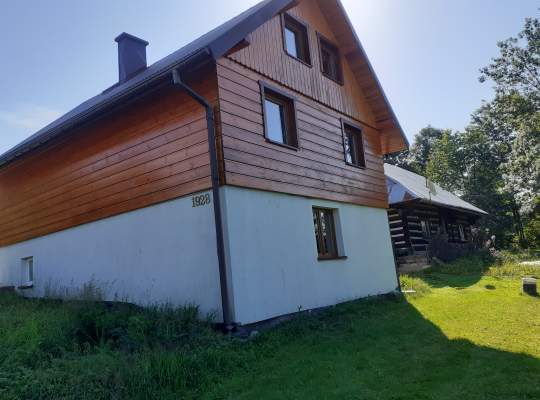 Widok zewnętrzny domu - biała podmurówka, budynek drewniany