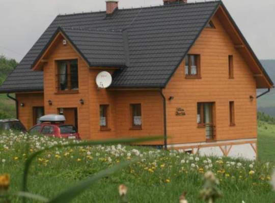 Widok zewnętrzny drewnianego domu z szarym dachem