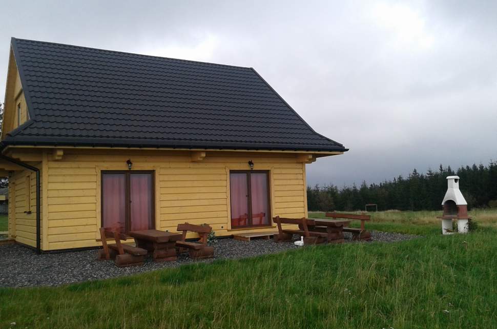 Widok zewnętrzny domku - drewniany, niewielki obiekt, szary dach