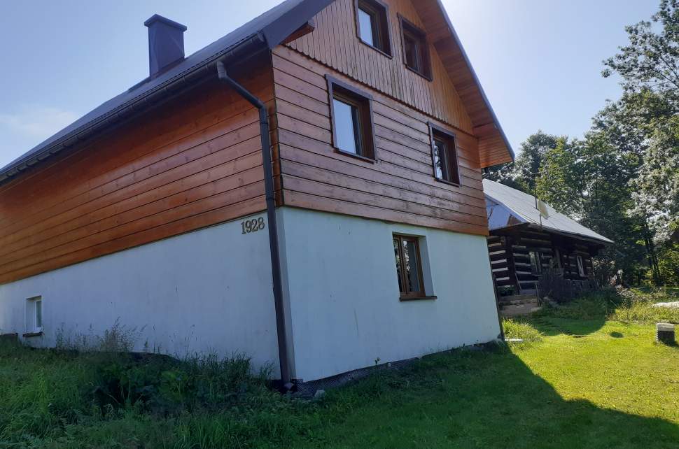 Widok zewnętrzny domu - biała podmurówka, budynek drewniany