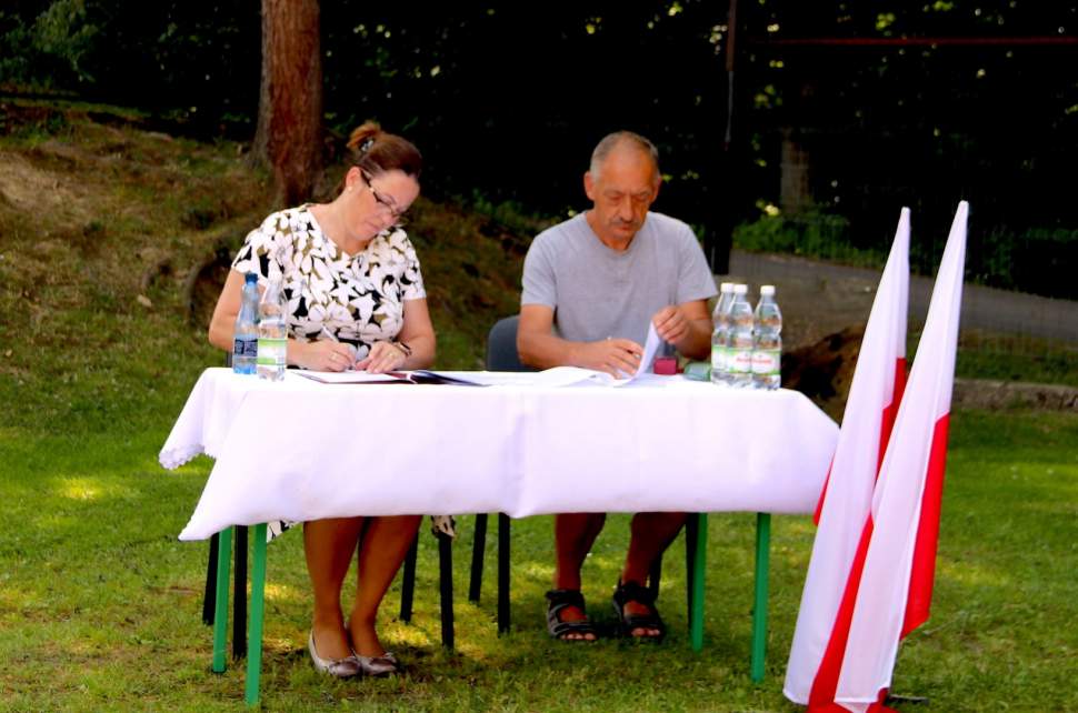 Łucja Michałek wójt gminy Istebna i Witold Ryszka podczas podpisania umowy na rozbudowę wodociągu w Koniakowie Rastoce. Z przodu flagi Polski, w tle las.