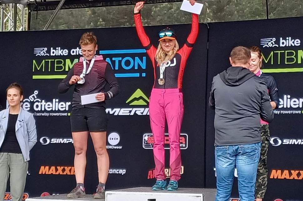 Anna Kaczmarzyk na pierwszym miejscu podium, widoczne jeszcze trzy zawodniczki oraz osoba gratulująca