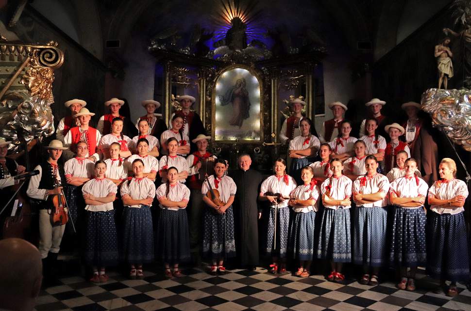 Zespół "Istebna", w środku ksiądz dziekan Tadeusz Pietrzyk, z prawej prowadząca koncert Aneta Legierska, w tle obraz Dobrego Pasterza