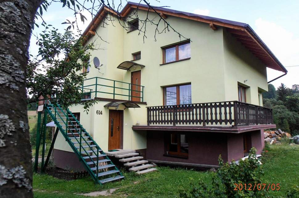 Widok zewnętrzny domu; jasny tynk, schody, balkon