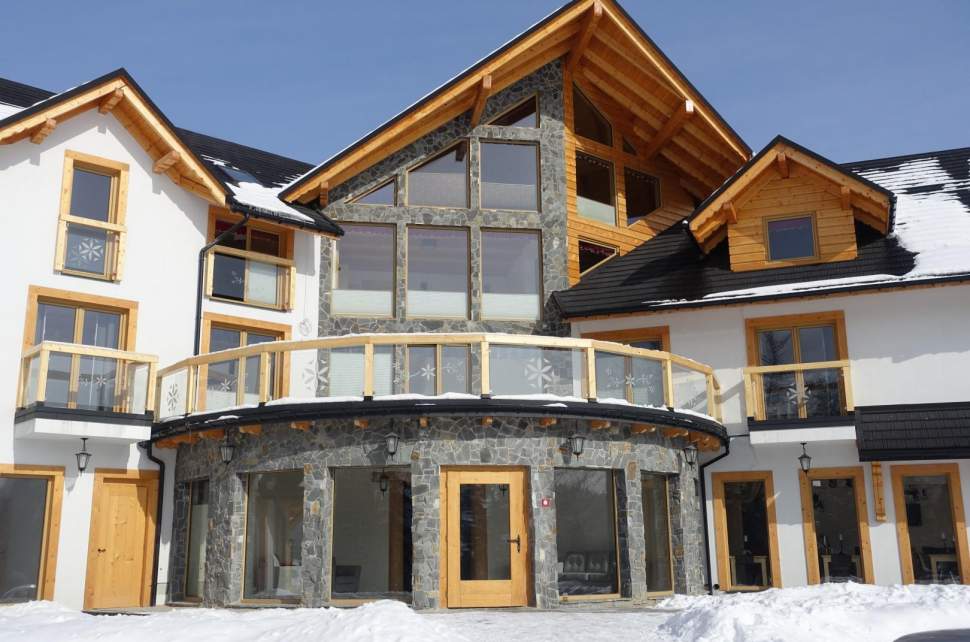 Widok zewnętrzny obiektu, znaczne przeszklenie, biały tynk i szary kamień